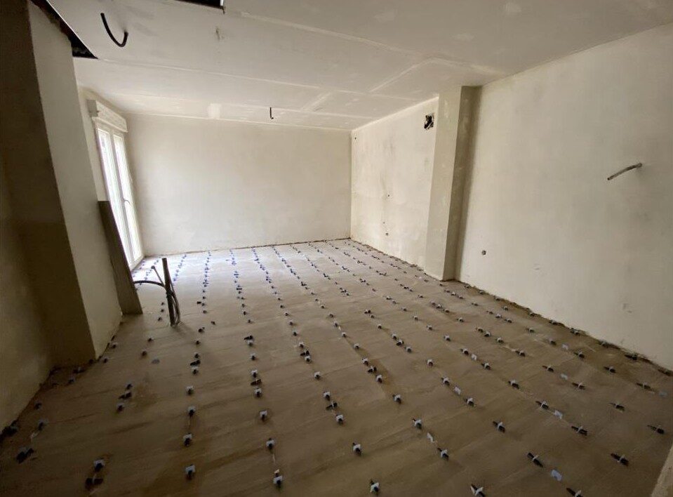 Salón en reforma con suelo en proceso de colocación de baldosas cerámicas y paredes enlucidas