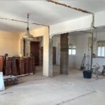 Espacio interior en reforma con paredes demolidas, ladrillos apilados y estructuras de soporte visibles