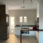 Cocina reformada con muebles modernos en blanco, encimera oscura y electrodomésticos integrados