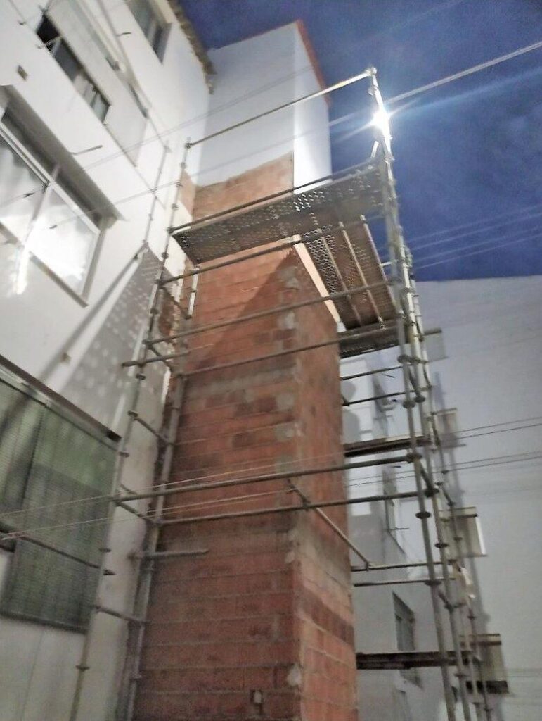 Fachada trasera de edificio en reforma con andamios metálicos instalados para el proceso de instalación de ascensor